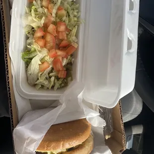 a sandwich and salad in a styrofoam container