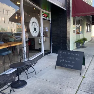 a sidewalk with tables and chairs