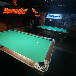 two pool tables and a neon sign