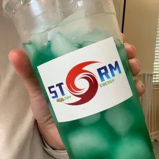 a person holding a plastic cup filled with green liquid