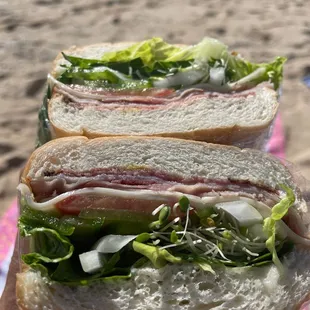 a person holding a sandwich on the beach