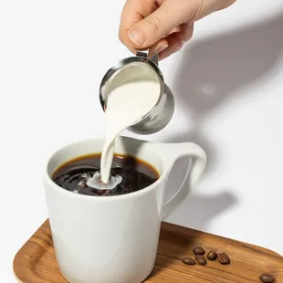 a person pouring milk into a cup