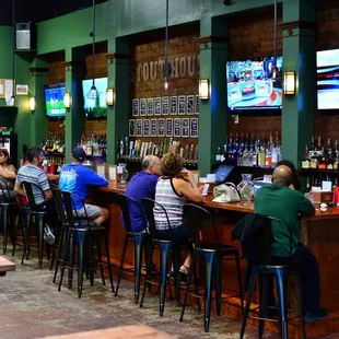 people sitting at the bar watching tvs