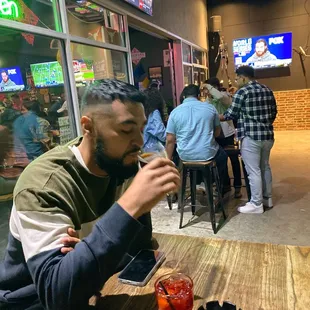 a man sitting at a table drinking a drink