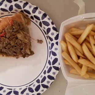 Half of a small cheesesteak with fries