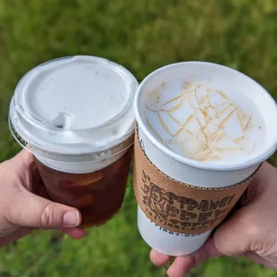 two hands holding two cups of coffee
