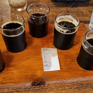 five glasses of beer on a wooden tray