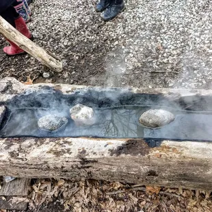 Old fashioned cooking: fired-hot stones in carved out log