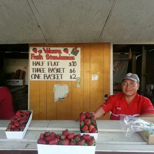 a woman selling strawberries at a fruit stand