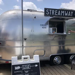 a woman standing in front of a coffee trailer