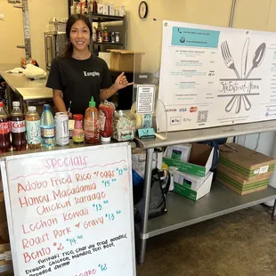 a woman standing behind a table of food