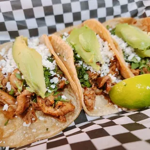 three tacos on a checkered tray