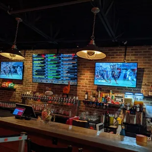 a bar with a brick wall and multiple televisions