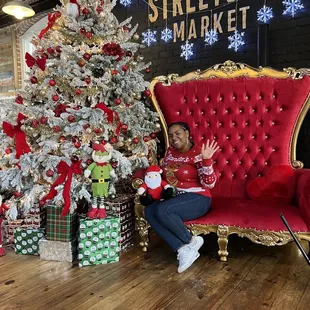 a woman sitting on a red chair in front of a christmas tree