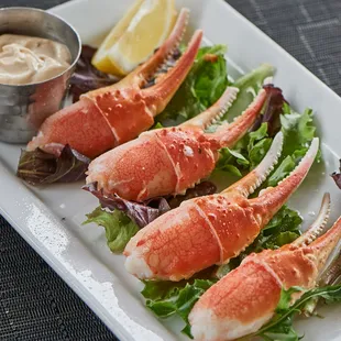 crab legs on a plate with lettuce and lemon wedges