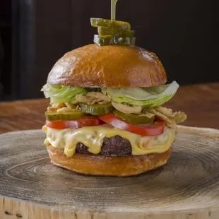 The STRIPSTEAK Burger with lettuce, tomato, crunchy onions, american cheese, pickles, bacon, secret sauce