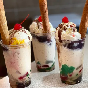 three dessert cups with ice cream, fruit, and chocolate