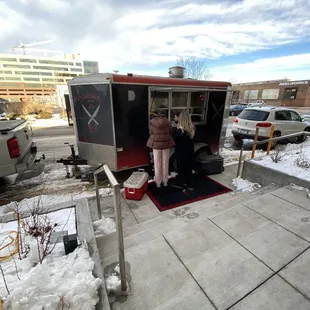 a woman standing in front of a food truck