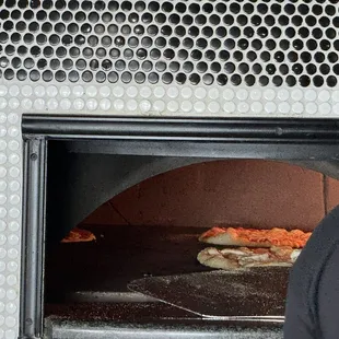 a man taking a pizza out of the oven