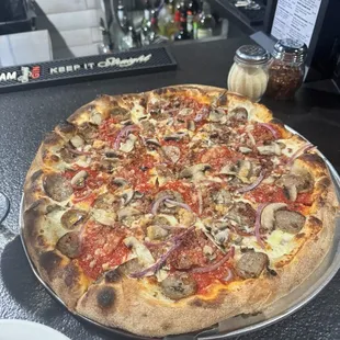 Large pizza with sausage, bacon, red onion, mushrooms, and minced garlic.