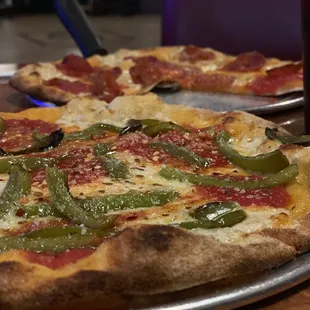 Personal pizza with green peppers on one and pepperoni on the other.