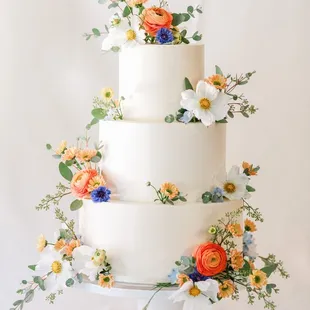 a three tiered cake with fresh flowers