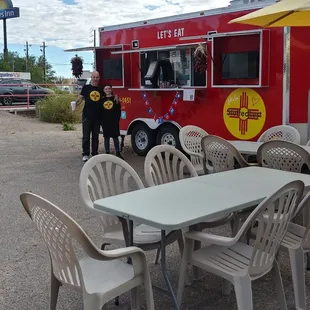 a table and chairs in front of a food truck