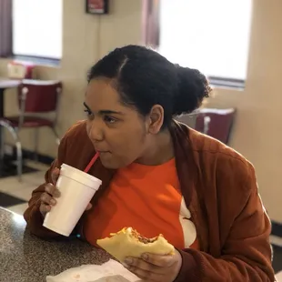 a woman sitting at a table eating a hot dog