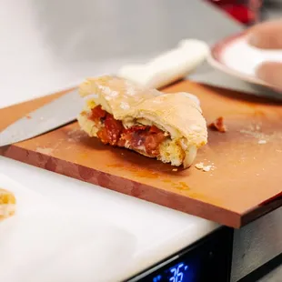 a person cutting a sandwich on a cutting board