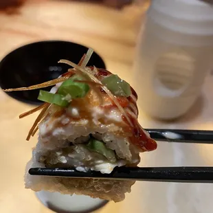 a piece of sushi with chopsticks