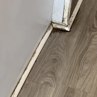 the corner of a room with a door and a wood floor