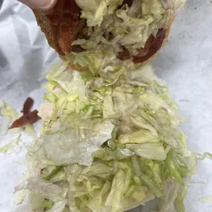 a hand holding a half eaten sub sandwich