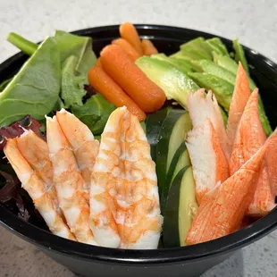 shrimp, carrots, cucumber, and lettuce in a bowl