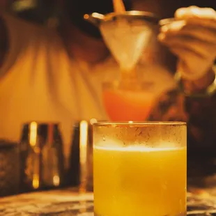 a person pouring a drink into a glass
