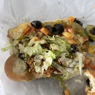 a sandwich with lettuce, black olives, and tomatoes