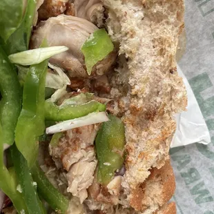 a half eaten sandwich with meat and vegetables