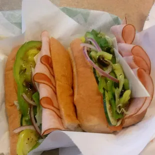 two sub sandwiches with pickles and onions