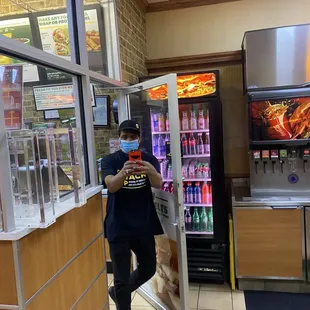 a man in a face mask standing in front of a vending machine