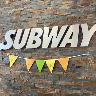 a subway sign on a brick wall