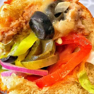 a hand holding a sandwich with vegetables