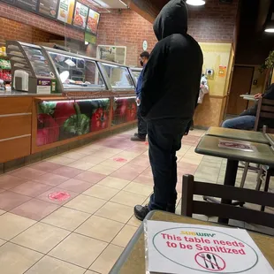 a man in a hoodie standing at a counter