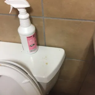 a white toilet with a spray bottle on top of it