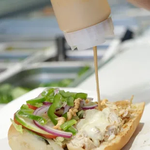 a person putting mustard on a sandwich