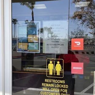 the reflection of a restroom sign in a window