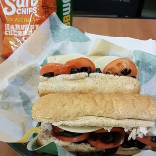 a sub sandwich with tomatoes and olives