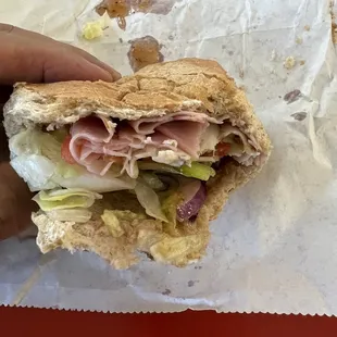 a hand holding a half eaten sandwich