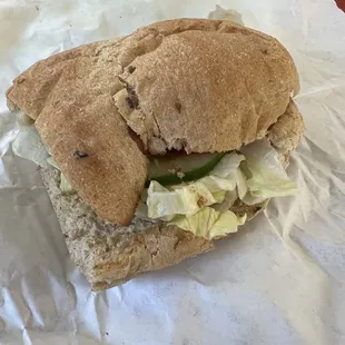 a half eaten sandwich with lettuce and pickles