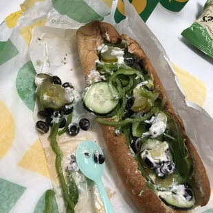 a hot dog with pickles, cucumbers, and cheese