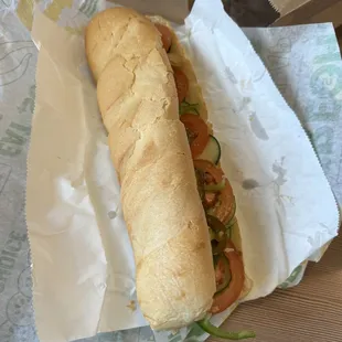 a sub sandwich in a wrapper on a table