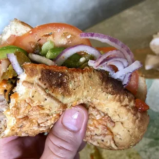 a hand holding a half eaten sandwich